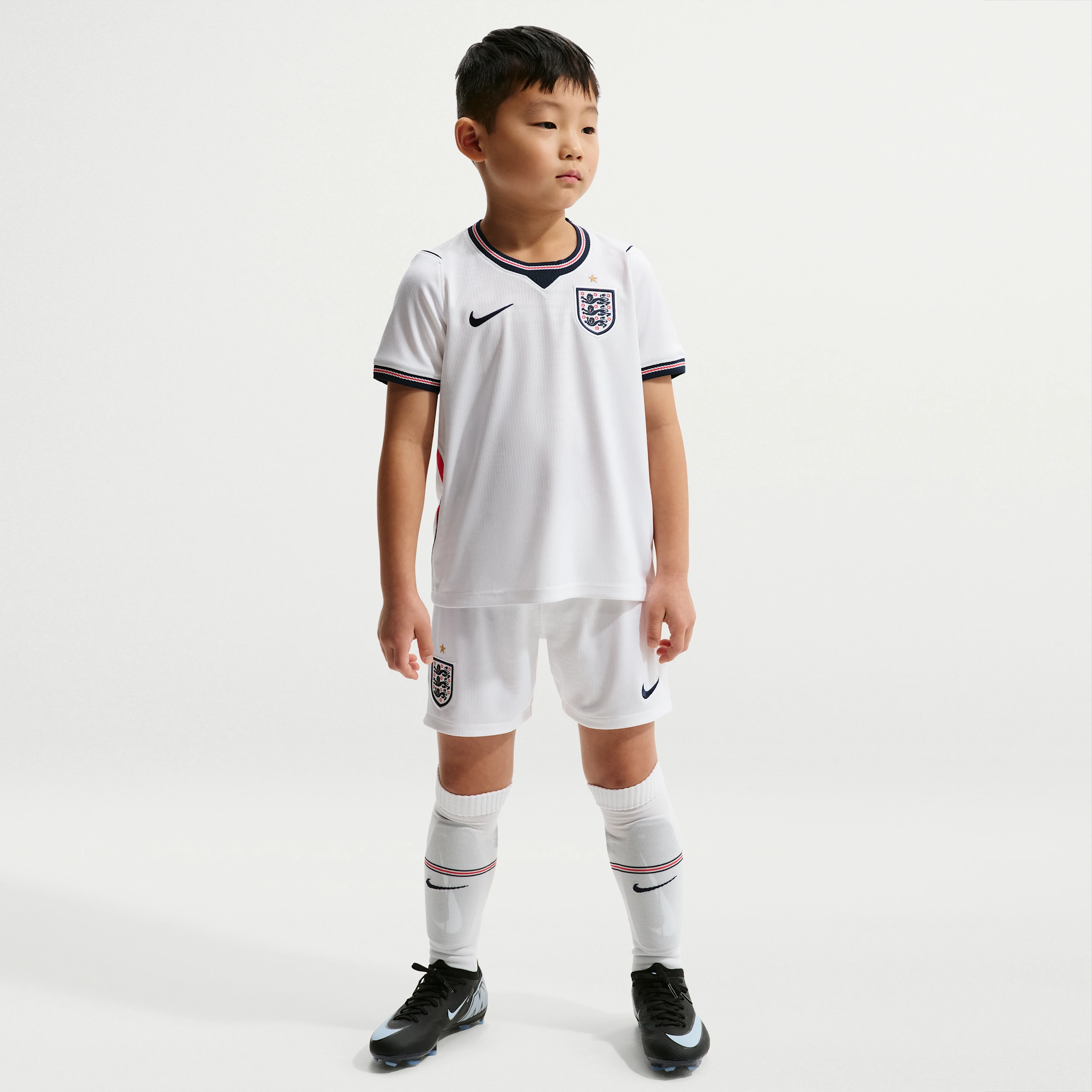 Mini-kit domicile Nike de l'équipe d'Angleterre 2026 pour enfant avec maillot, short et chaussettes blancs.
